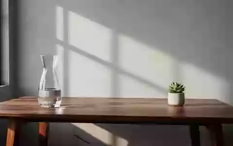 Ein minimalistischer, aufgeräumter Arbeitsplatz mit einer Glaskaraffe und einer Pflanze vor einer schlichten Wand. - Foto: über boerse-global.de