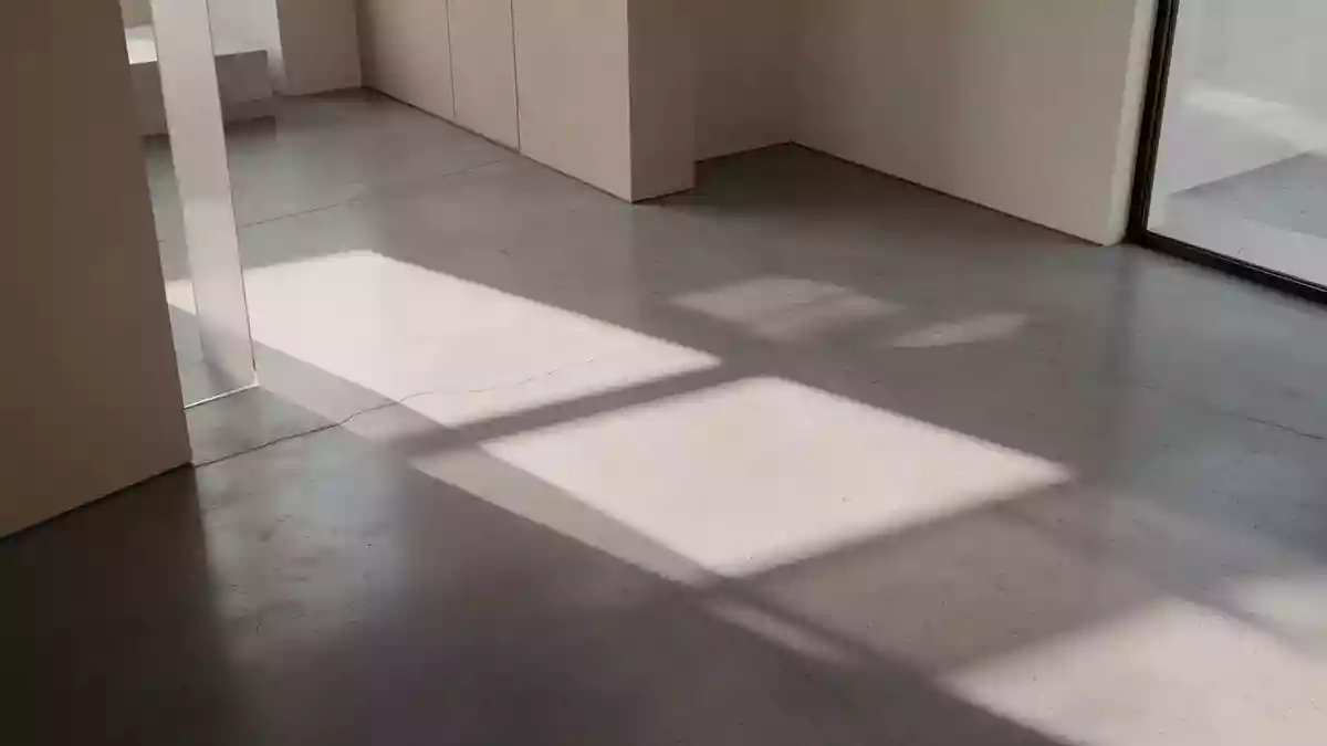 Minimalistisches Architektur-Interieur mit geometrischen Schatten auf einem polierten Betonboden bei natürlichem Licht. Illustration mit AI erstellt.