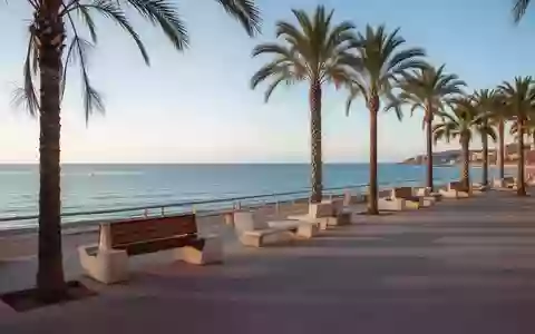 Die leere Promenade von Lloret de Mar am Mittelmeer mit Palmen und Steinbänken im morgendlichen Licht. - Foto: über boerse-global.de