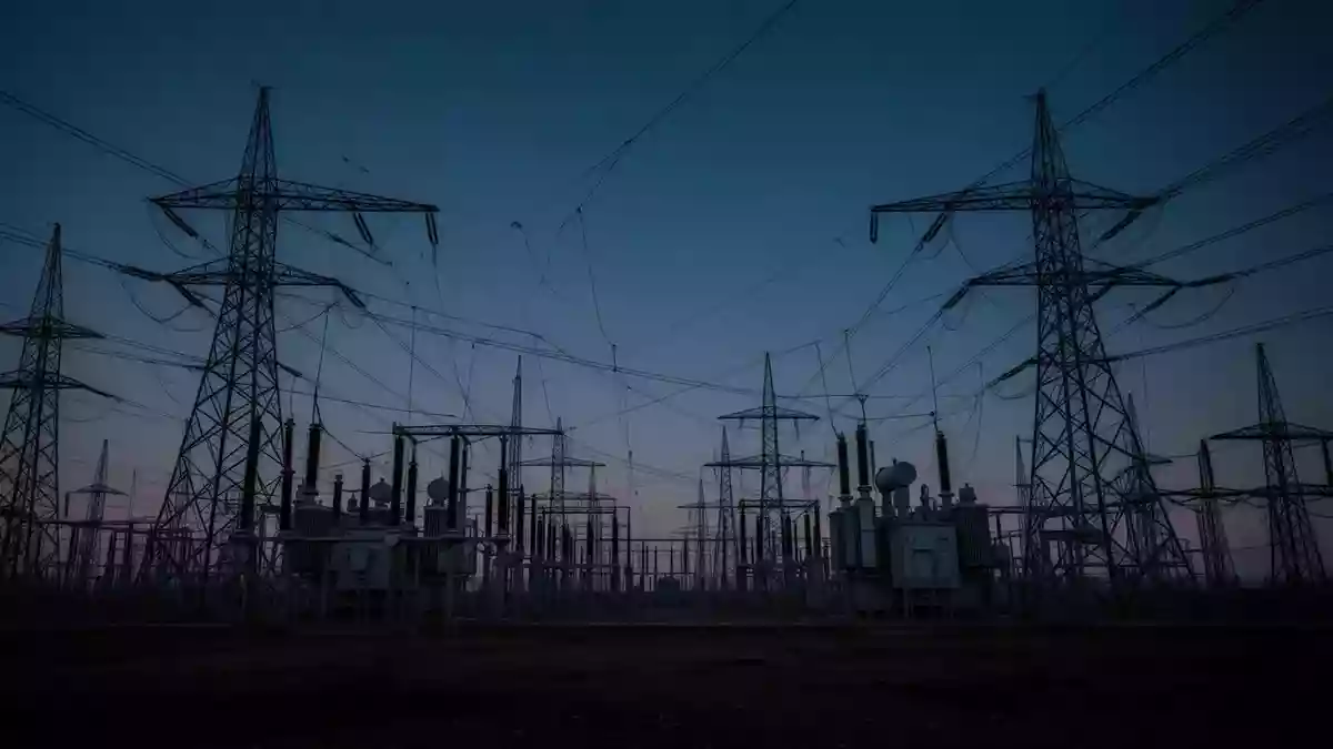 Ein weitläufiges Hochspannungsumspannwerk in der Dämmerung, das die kritische Infrastruktur vor dem Hintergrund eines dunklen Himmels zeigt. Illustration mit AI erstellt.