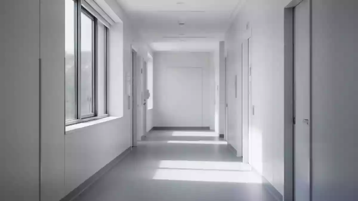 Ein leerer, heller Krankenhausflur mit minimalistischer Architektur und sanftem Tageslichteinfall. Illustration mit AI erstellt.
