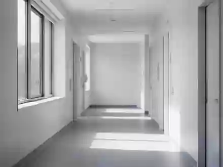Ein leerer, heller Krankenhausflur mit minimalistischer Architektur und sanftem Tageslichteinfall. - Foto: über boerse-global.de
