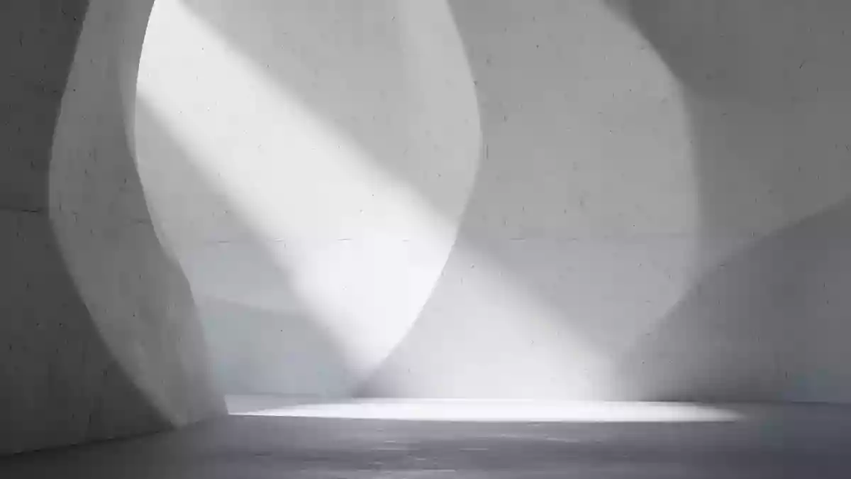 Minimalistisch gestaltete, lichtdurchflutete Innenarchitektur mit weichen Schattenwürfen auf einer geschwungenen Wand. Illustration mit AI erstellt.