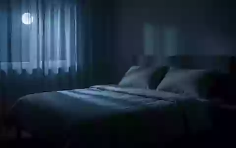 Ein ruhig wirkendes, in sanftes blaues Mondlicht getauchtes Schlafzimmer bei Nacht mit einem unbenutzten, ordentlich gemachten Bett. - Foto: ĂĽber boerse-global.de