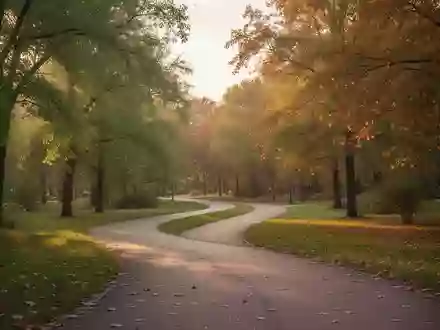 Ein geschwungener Parkweg im warmen Licht der Abendsonne, umgeben von Bäumen und herbstlichem Laub. - Foto: über boerse-global.de