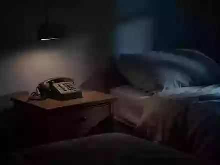 Ein nächtliches Schlafzimmer mit einem alten Telefon auf dem Nachttisch im gedimmten Licht. - Foto: über boerse-global.de