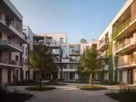 Ein moderner Gemeindebau in Wien mit begrünten Fassaden und einem gepflegten Innenhof bei Sonnenuntergang. - Foto: über boerse-global.de