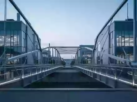 Eine moderne Architekturbrücke zwischen zwei Forschungsgebäuden in der Abenddämmerung. - Foto: über boerse-global.de