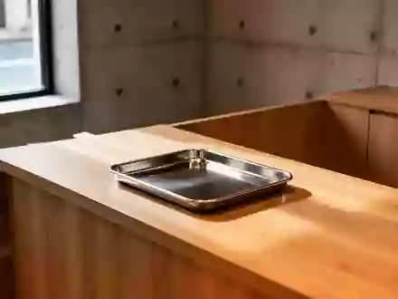 Ein minimalistischer Holztresen mit einer leeren Metallschale in einem schlichten, modernen Verkaufsraum bei natürlichem Licht. - Foto: über boerse-global.de