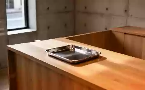 Ein minimalistischer Holztresen mit einer leeren Metallschale in einem schlichten, modernen Verkaufsraum bei natürlichem Licht. - Foto: über boerse-global.de