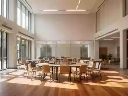 Ein heller, minimalistischer Gemeinschaftsraum mit Holzfußboden, leeren Stühlen und Tischen, durchflutet von natürlichem Licht. - Foto: über boerse-global.de
