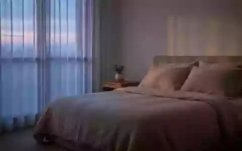 Ein ruhiges, minimalistisch eingerichtetes Schlafzimmer mit neutraler Bettwäsche und sanftem Tageslicht, das eine Atmosphäre der Erholung vermittelt. - Foto: über boerse-global.de