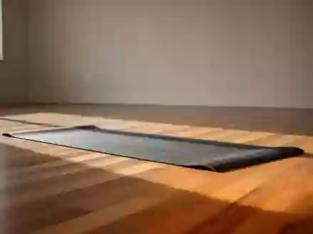 Ein minimalistischer Fitnessraum mit einer ausgerollten Yogamatte auf einem hellen Holzboden in natürlichem Licht. - Foto: über boerse-global.de
