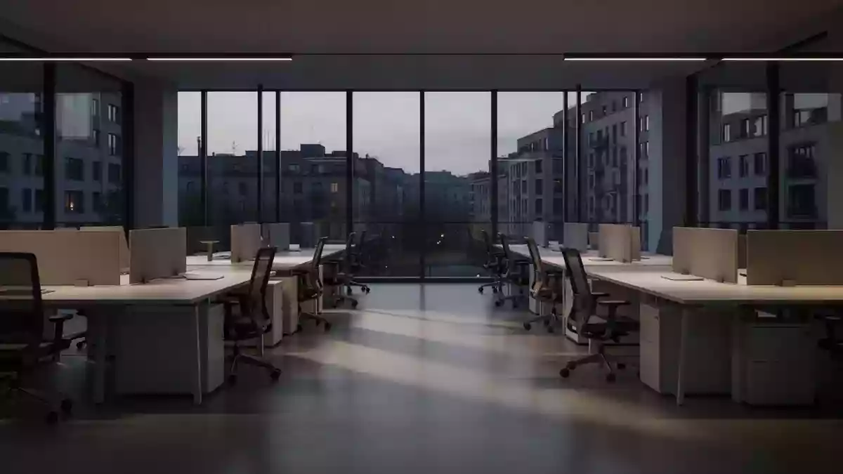 Ein leerer, modern gestalteter Großraumbürobereich in der Dämmerung mit minimalistischen Arbeitsplätzen und natürlichem Licht. Illustration mit AI erstellt.