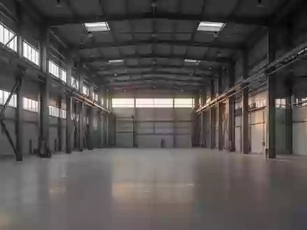 Leere, moderne Industriehalle mit hohen Decken und Stahlträgern bei Dämmerlicht. - Foto: über boerse-global.de
