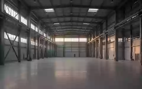 Leere, moderne Industriehalle mit hohen Decken und Stahlträgern bei Dämmerlicht. - Foto: über boerse-global.de