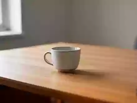 Ein minimalistischer, aufgeräumter Arbeitsplatz mit einer leeren Tasse auf einem Holztisch bei natürlichem Licht. - Foto: über boerse-global.de