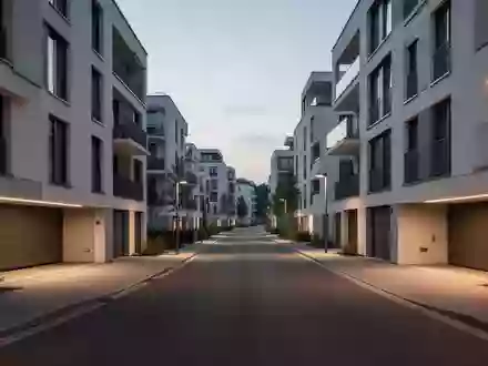 Eine moderne Wohnstraße bei Dämmerung mit architektonisch klaren Gebäudefassaden und sauberer Straßenführung ohne Fahrzeuge. - Foto: über boerse-global.de