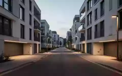 Eine moderne Wohnstraße bei Dämmerung mit architektonisch klaren Gebäudefassaden und sauberer Straßenführung ohne Fahrzeuge. - Foto: über boerse-global.de