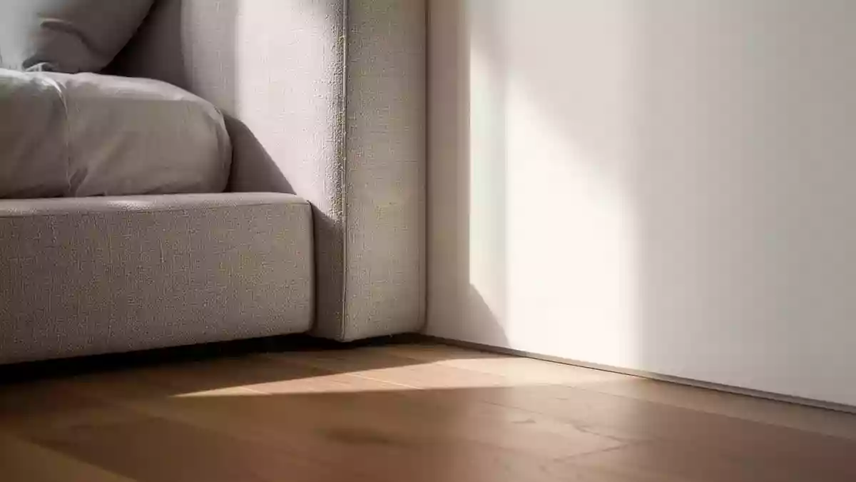 Ein minimalistisches, sonnendurchflutetes Schlafzimmer mit Fokus auf sauberen Texturen an einer Wand und einem Boden. Illustration mit AI erstellt.