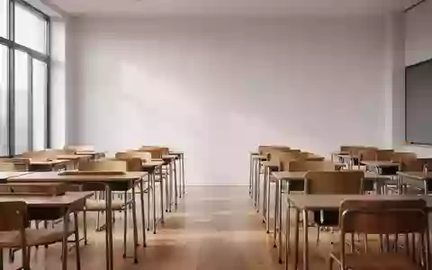Ein leerer, sonnendurchfluteter Klassenraum mit schlichten Holztischen und Stühlen in einer ruhigen, minimalistischen Atmosphäre. - Foto: über boerse-global.de