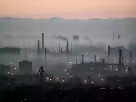 Dichte Dunstglocke über einer städtischen Skyline bei Dämmerung, die die Sicht durch Feinstaubpartikel in der Luft trübt. - Foto: über boerse-global.de