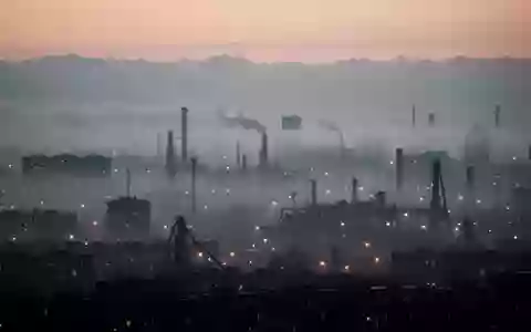 Dichte Dunstglocke über einer städtischen Skyline bei Dämmerung, die die Sicht durch Feinstaubpartikel in der Luft trübt. - Foto: über boerse-global.de