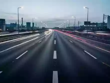 Eine leere, moderne Autobahn bei Dämmerung mit Lichtspuren von vorbeifahrendem Verkehr und Fokus auf der Infrastruktur. - Foto: über boerse-global.de