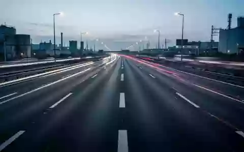 Eine leere, moderne Autobahn bei Dämmerung mit Lichtspuren von vorbeifahrendem Verkehr und Fokus auf der Infrastruktur. - Foto: über boerse-global.de