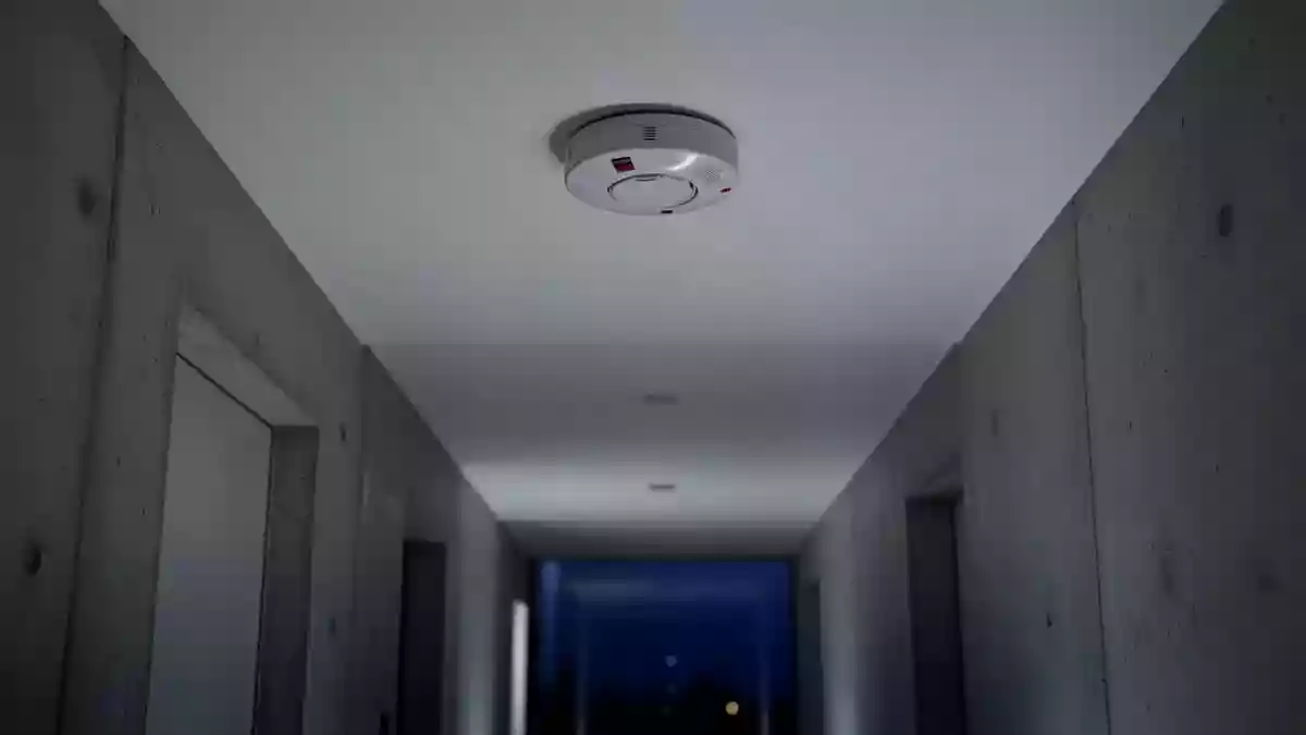 Ein minimalistischer Flur mit einem an der Decke montierten Rauchmelder in einer ruhigen, architektonischen Umgebung. Illustration mit AI erstellt.