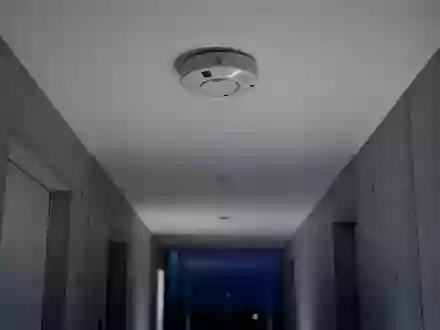 Ein minimalistischer Flur mit einem an der Decke montierten Rauchmelder in einer ruhigen, architektonischen Umgebung. - Foto: über boerse-global.de