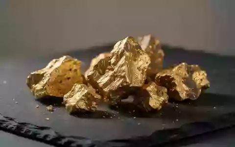 Rohgoldstücke auf einer dunklen, texturierten Oberfläche in einer professionellen Bergbauumgebung. - Foto: über boerse-global.de