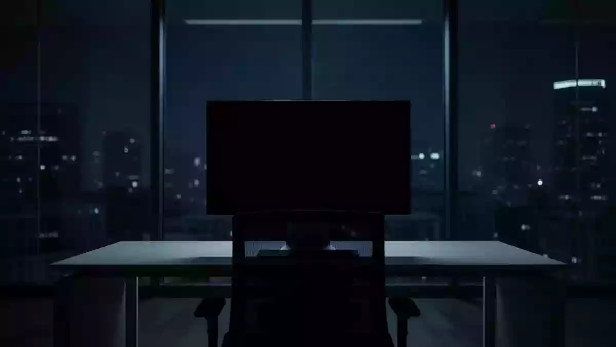 Ein dunkler, moderner Büroarbeitsplatz mit einem ausgeschalteten Computerbildschirm in einer minimalistischen Umgebung. Illustration mit AI erstellt.