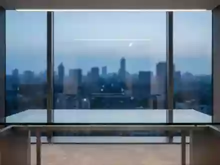 Ein minimalistischer, leerer Schreibtisch vor einem Fenster mit Blick auf eine Stadt bei Dämmerung. - Foto: über boerse-global.de