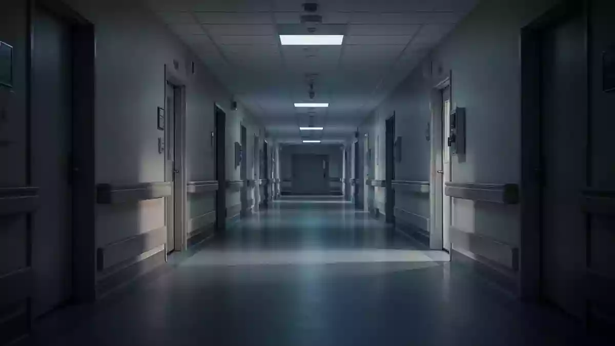 Ein leerer, steriler Krankenhausflur bei Dämmerung mit langen Schatten auf dem Boden. Illustration mit AI erstellt.