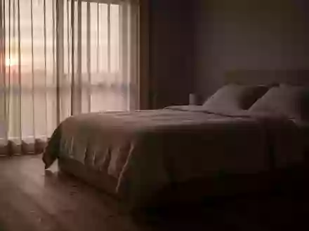 Ein minimalistisch eingerichtetes, ruhiges Schlafzimmer bei Tagesanbruch, das eine Atmosphäre der Erholung vermittelt. - Foto: über boerse-global.de
