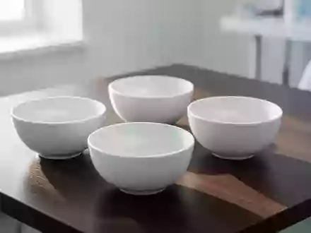 Minimalistische weiße Schalen auf einem dunklen Holztisch in einer hellen, sterilen Umgebung. - Foto: über boerse-global.de