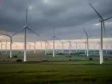 Weites Windkraftfeld unter einem bewölkten Himmel, das die großflächige Stromerzeugung durch erneuerbare Energien symbolisiert. - Foto: über boerse-global.de
