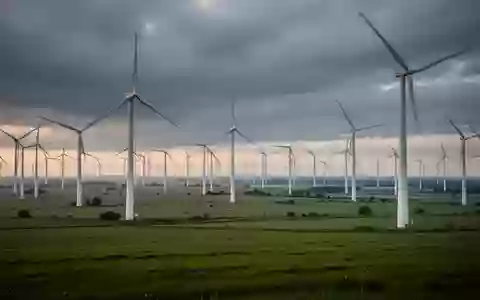 Weites Windkraftfeld unter einem bewölkten Himmel, das die großflächige Stromerzeugung durch erneuerbare Energien symbolisiert. - Foto: über boerse-global.de