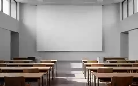 Ein leerer, minimalistischer Hörsaal mit Holztischen und einer leeren Projektionswand in einem modernen Bildungsgebäude. - Foto: über boerse-global.de