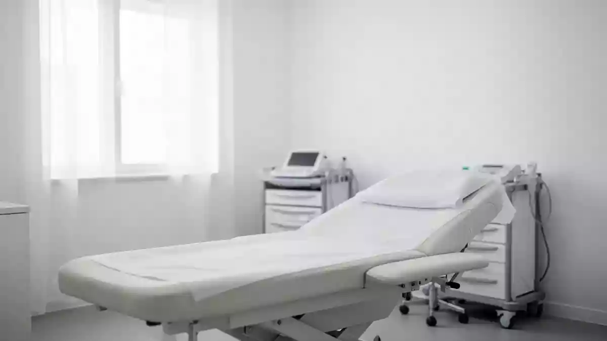 Ein minimalistischer, heller Behandlungsraum in einer Klinik mit neutralen Oberflächen und sanftem Tageslicht. Illustration mit AI erstellt.