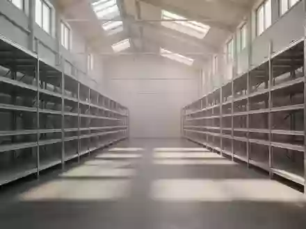 Ein minimalistisches, leeres Logistikzentrum mit langen Regalreihen und einfallendem Tageslicht auf einem Betonboden. - Foto: über boerse-global.de
