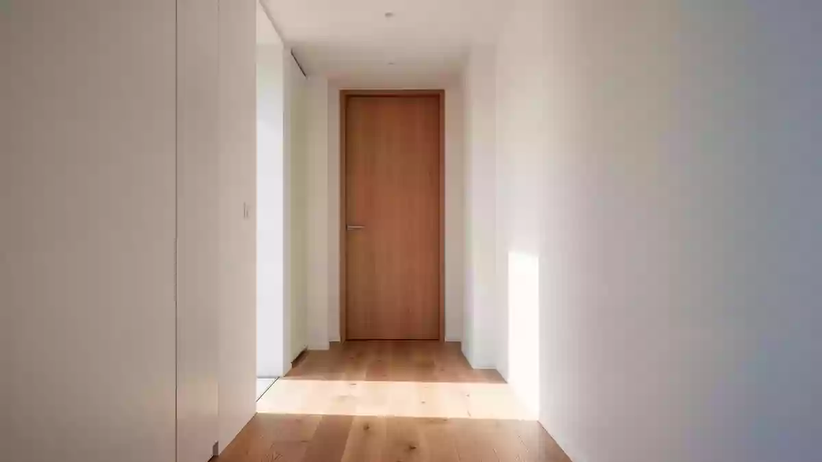 Ein heller, minimalistischer Flur in einem Wohngebäude mit Holzboden und einer geschlossenen Zimmertür. Illustration mit AI erstellt.