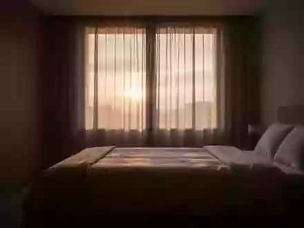 Ein minimalistisch eingerichtetes, in sanftes Morgenlicht getauchtes Schlafzimmer bei Sonnenaufgang. - Foto: über boerse-global.de