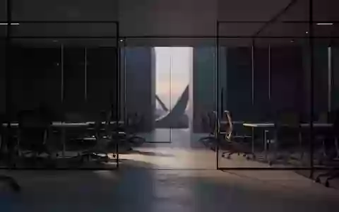 Ein minimalistisch eingerichteter, leerer Büroflur bei Dämmerung mit dunklen Glaswänden und Schattenwürfen auf dem Boden. - Foto: über boerse-global.de