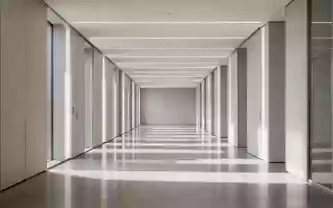 Ein minimalistischer, heller Flur mit klaren Linien und rhythmischem Lichteinfall, der Struktur und Ordnung symbolisiert. - Foto: über boerse-global.de