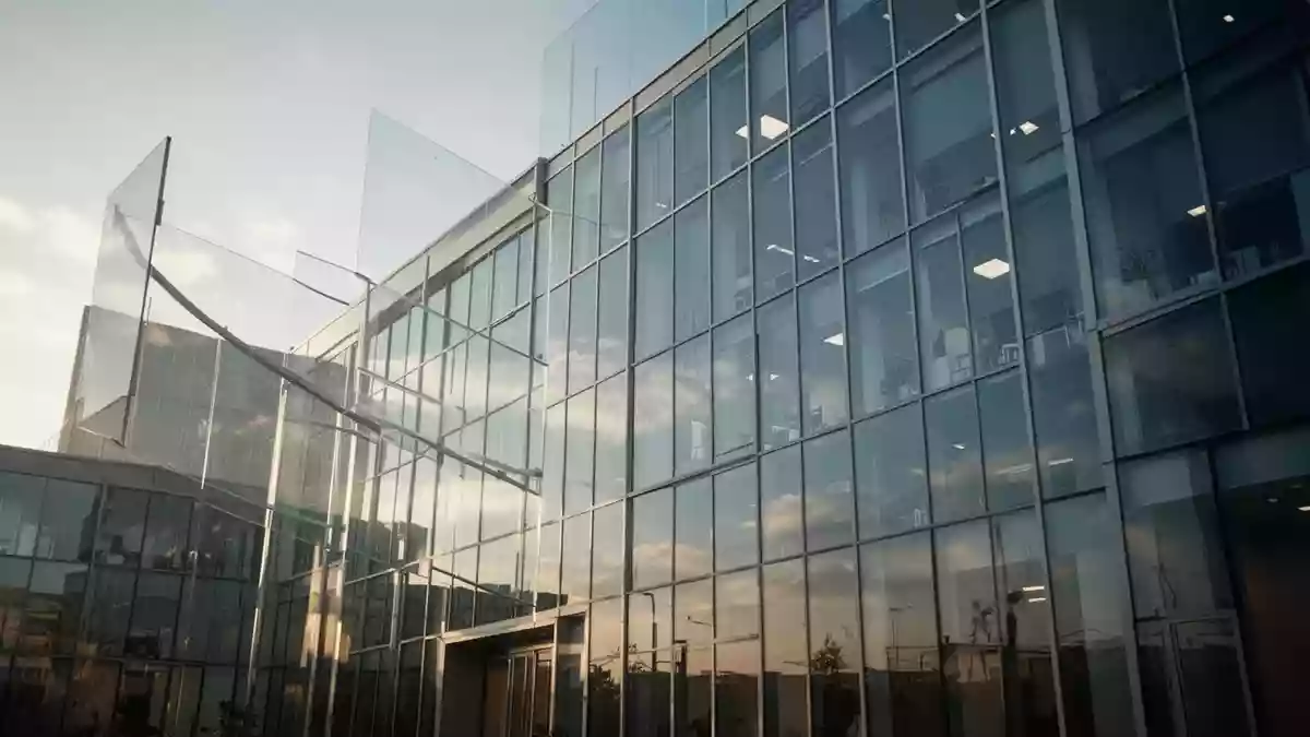 Ein modernes Bürogebäude aus Glas bei hellem Tageslicht, das Stabilität und wirtschaftliches Wachstum symbolisiert. Illustration mit AI erstellt.