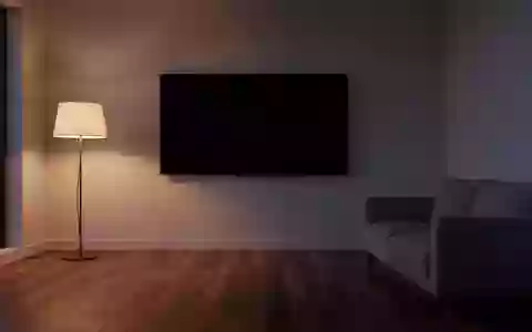 Ein minimalistisch eingerichtetes Wohnzimmer mit einem ausgeschalteten, leeren Fernsehbildschirm an einer kahlen Wand. - Foto: über boerse-global.de