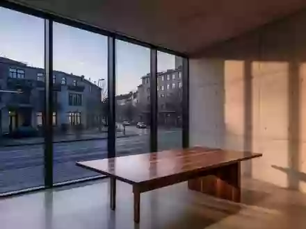 Ein minimalistisches, modernes Büro mit großen Fenstern und Blick auf eine ruhige Straße in der Abenddämmerung. - Foto: über boerse-global.de