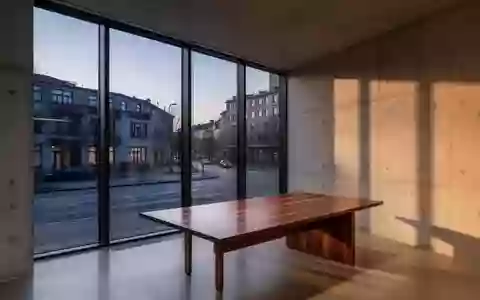 Ein minimalistisches, modernes Büro mit großen Fenstern und Blick auf eine ruhige Straße in der Abenddämmerung. - Foto: über boerse-global.de